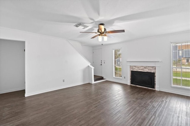 unfurnished living room featuring a stone fireplace, crown molding, ceiling fan, and dark hardwood / wood-style floors