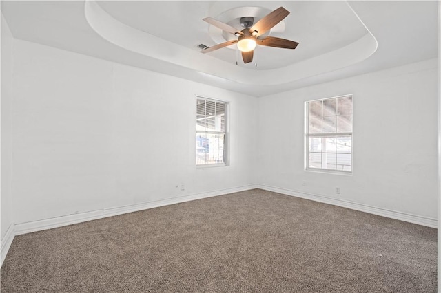 spare room featuring ceiling fan, carpet floors, and a tray ceiling