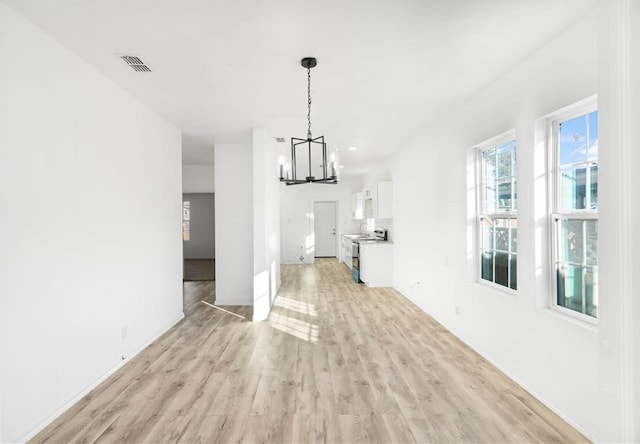 unfurnished living room with a chandelier and light hardwood / wood-style floors