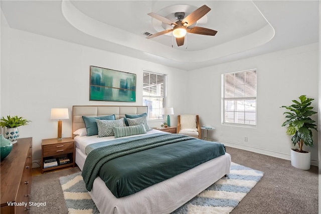 carpeted bedroom featuring a raised ceiling and ceiling fan