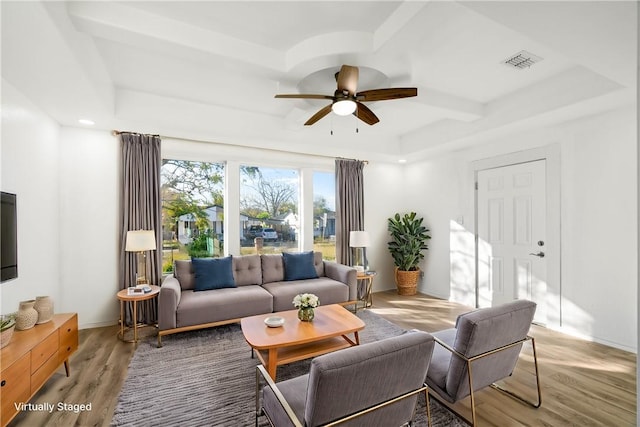 living room featuring a raised ceiling, light hardwood / wood-style flooring, and ceiling fan