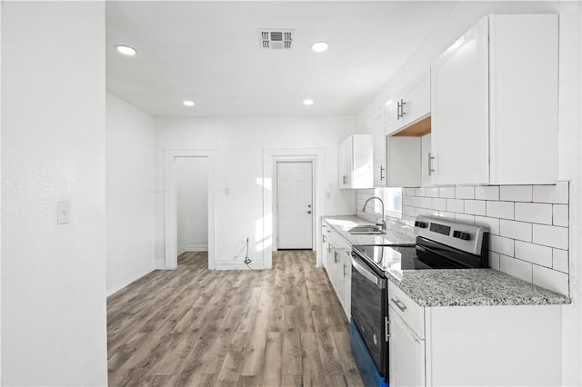 kitchen featuring stainless steel electric range, sink, light hardwood / wood-style flooring, light stone counters, and white cabinetry