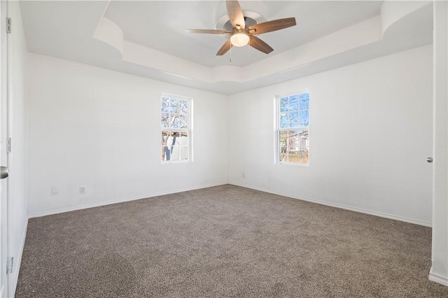 unfurnished room featuring carpet, a tray ceiling, and ceiling fan