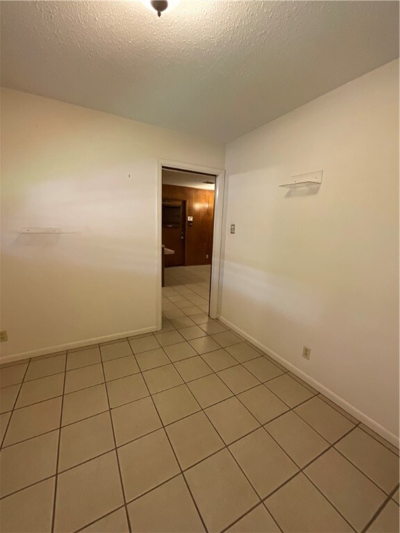 tiled spare room with a textured ceiling