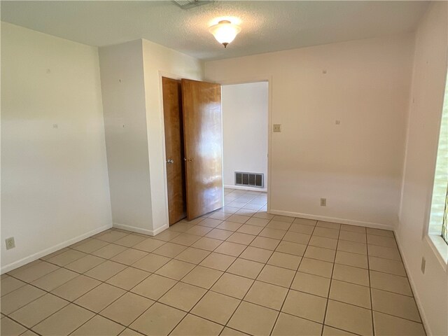 tiled empty room with a textured ceiling