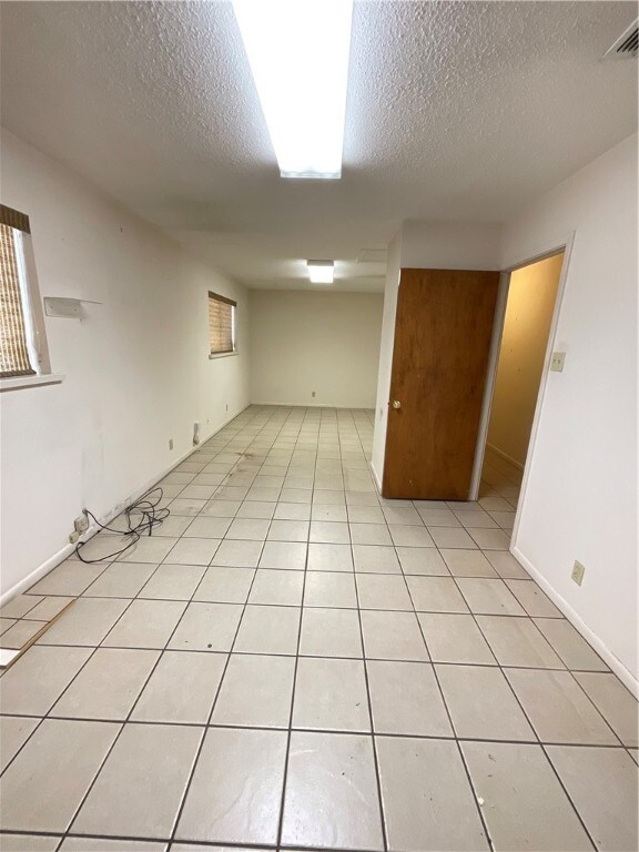 tiled empty room featuring a textured ceiling