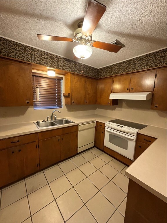 kitchen with a textured ceiling, white appliances, and sink