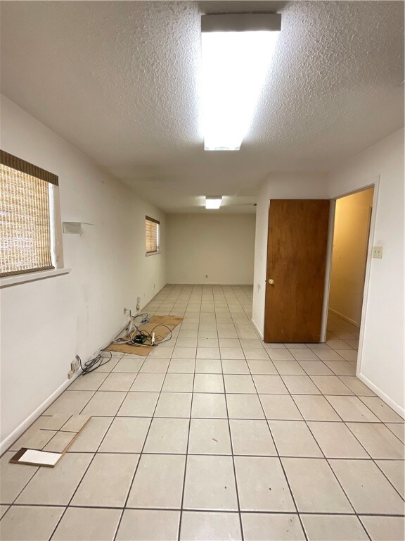 empty room featuring a textured ceiling and light tile patterned flooring