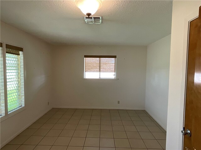 unfurnished room featuring light tile patterned flooring and a textured ceiling