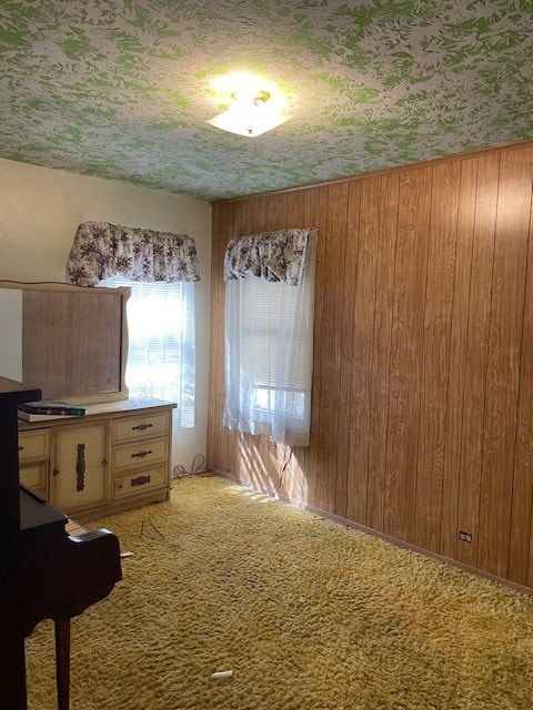 unfurnished dining area with carpet flooring and wood walls