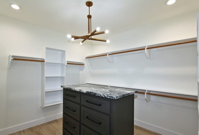 spacious closet featuring light wood-type flooring and an inviting chandelier