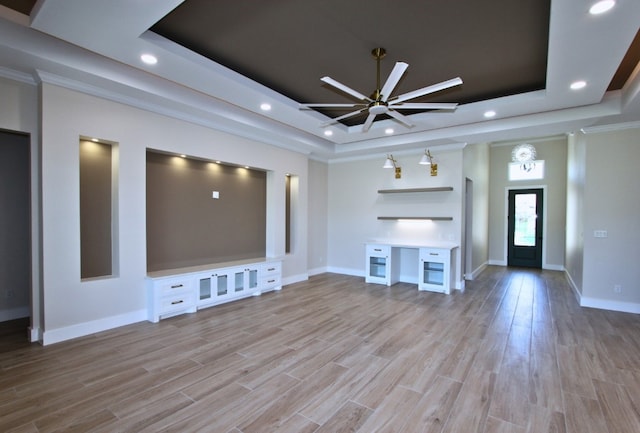 unfurnished living room with light hardwood / wood-style floors, a tray ceiling, and ceiling fan