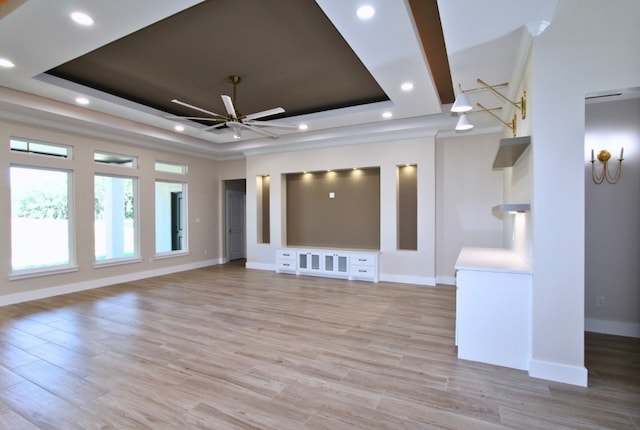 unfurnished living room featuring a tray ceiling, ceiling fan, and light hardwood / wood-style flooring