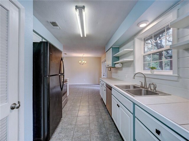 1305 S Whitney St, Aransas Pass, TX 78336 - kitchen with stainless steel appliances, a sink, open shelves, a chandelier, and white cabinetry