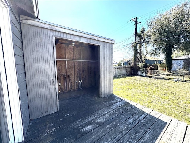 wooden terrace with a fenced backyard, a lawn, and an outbuilding