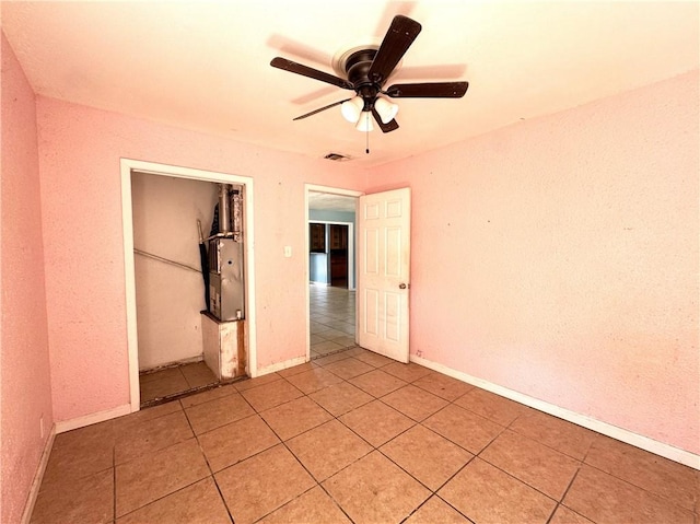 unfurnished bedroom with a closet, light tile patterned floors, baseboards, visible vents, and ceiling fan