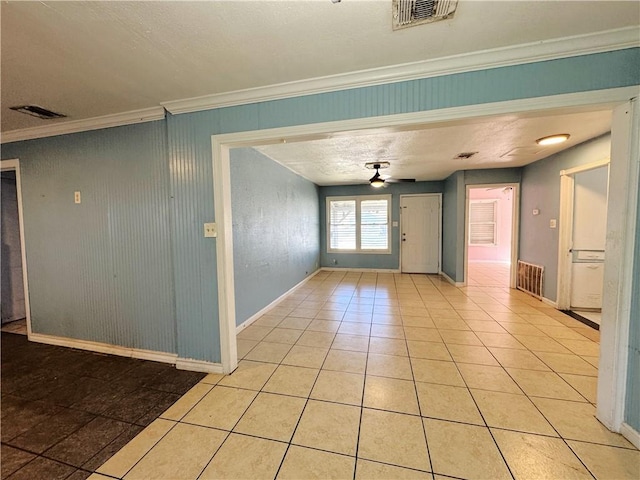 empty room featuring visible vents, baseboards, ornamental molding, a ceiling fan, and light tile patterned floors