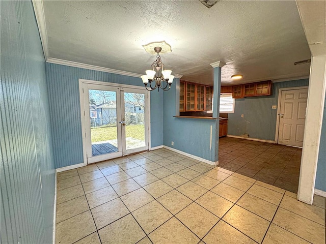 interior space with light tile patterned floors, a textured ceiling, ornamental molding, french doors, and a notable chandelier