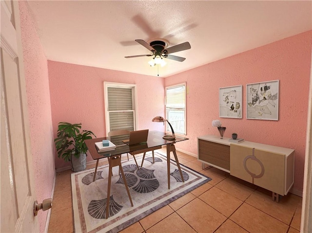 home office featuring ceiling fan, a textured wall, and light tile patterned floors