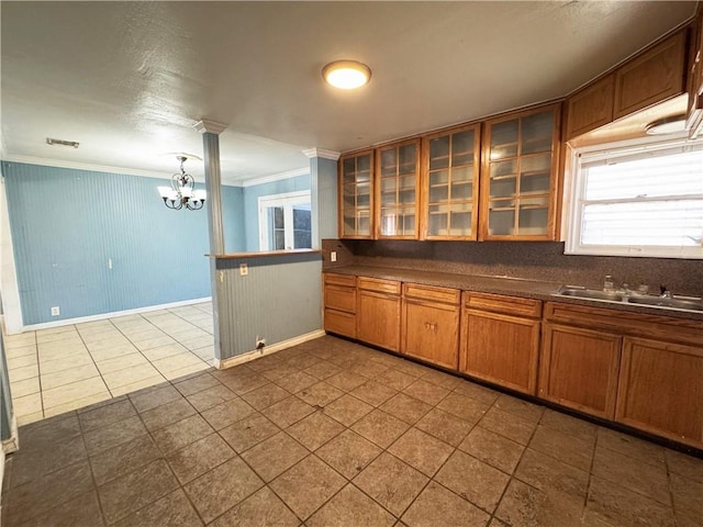 kitchen featuring a notable chandelier, a sink, brown cabinetry, dark countertops, and ornamental molding