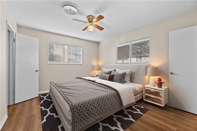 bedroom featuring ceiling fan, dark hardwood / wood-style floors, and a textured ceiling