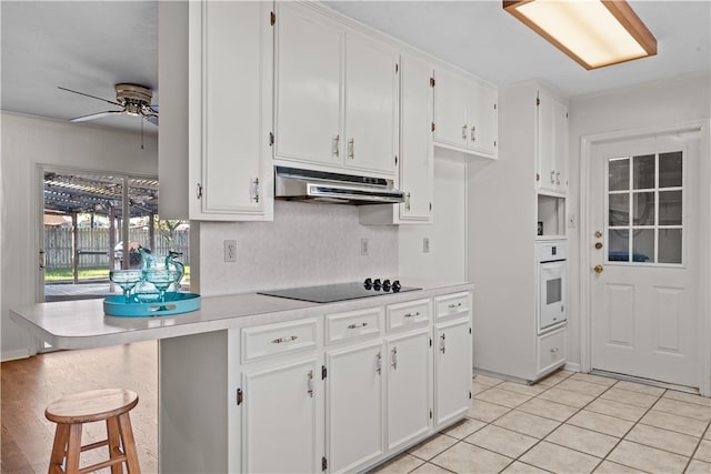 kitchen with light tile patterned flooring, ceiling fan, white oven, white cabinets, and black electric stovetop