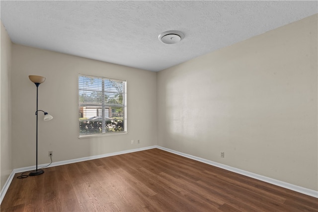 empty room with dark hardwood / wood-style floors and a textured ceiling