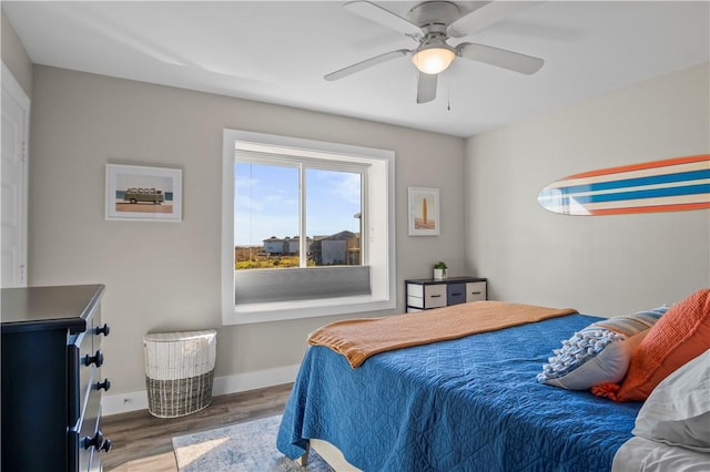 bedroom featuring a ceiling fan, baseboards, and wood finished floors