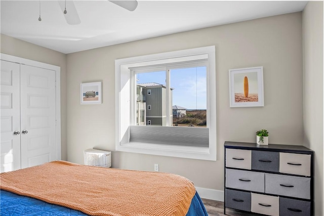 bedroom with ceiling fan, a closet, wood finished floors, and baseboards