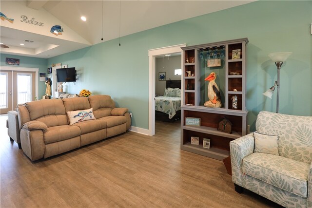 living room with lofted ceiling, french doors, and light hardwood / wood-style floors