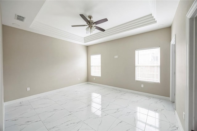 empty room featuring ornamental molding, ceiling fan, and a tray ceiling