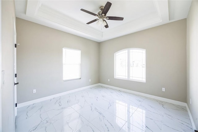 unfurnished room featuring plenty of natural light, a raised ceiling, and ceiling fan