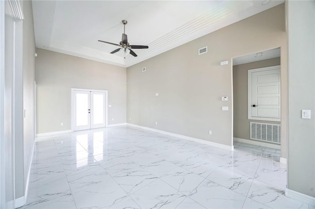 spare room with crown molding, ceiling fan, a towering ceiling, a tray ceiling, and french doors