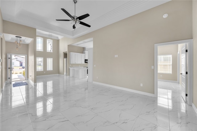 unfurnished living room with a high ceiling, ornamental molding, and ceiling fan