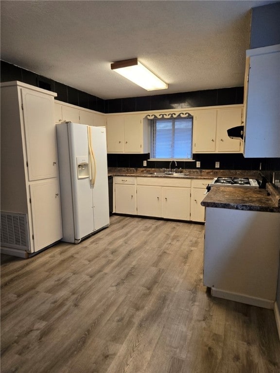 kitchen with white cabinets, hardwood / wood-style floors, a textured ceiling, and white fridge with ice dispenser