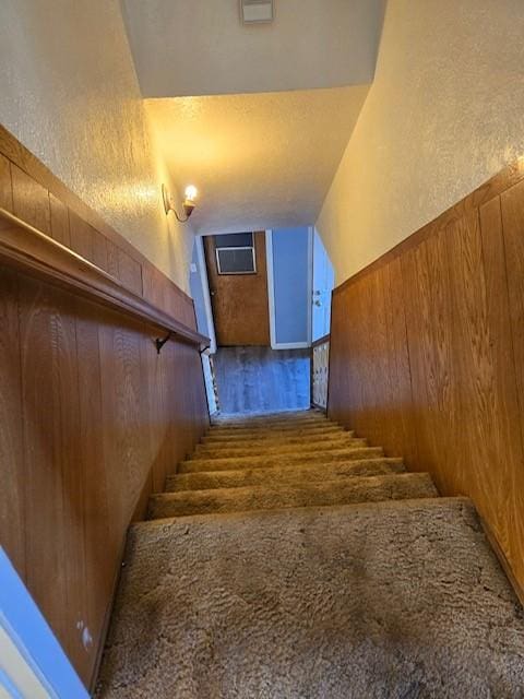 stairs featuring wood walls and wood-type flooring