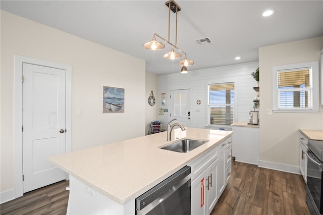 kitchen featuring white cabinetry, sink, stainless steel appliances, decorative light fixtures, and a kitchen island with sink