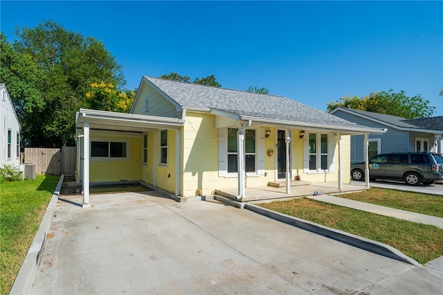 ranch-style home with cooling unit, a carport, and a porch