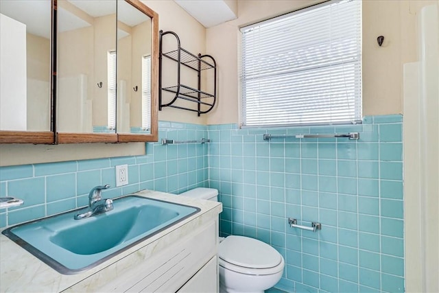 bathroom featuring vanity, toilet, and tile walls