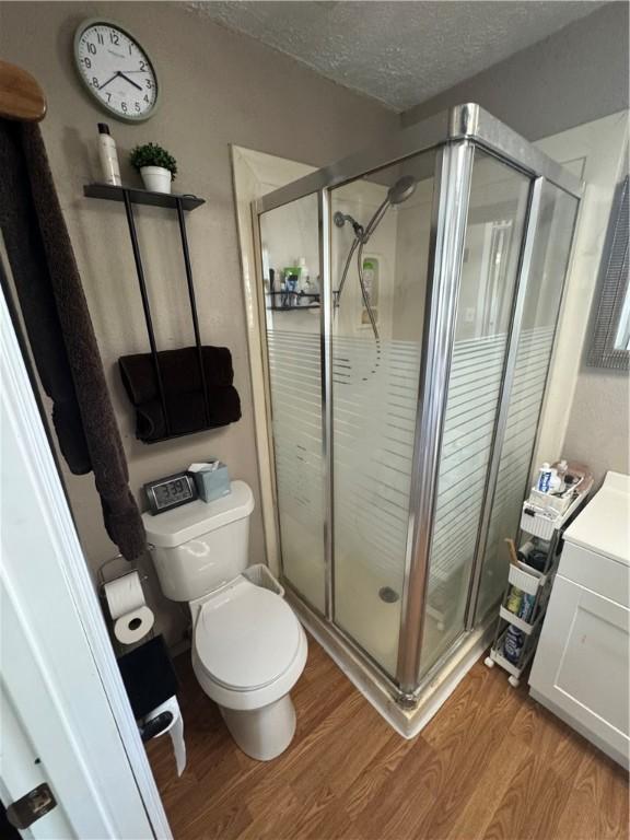 1210 Brentwood Dr, Corpus Christi, TX 78404 - full bath with a stall shower, a textured ceiling, wood finished floors, and toilet