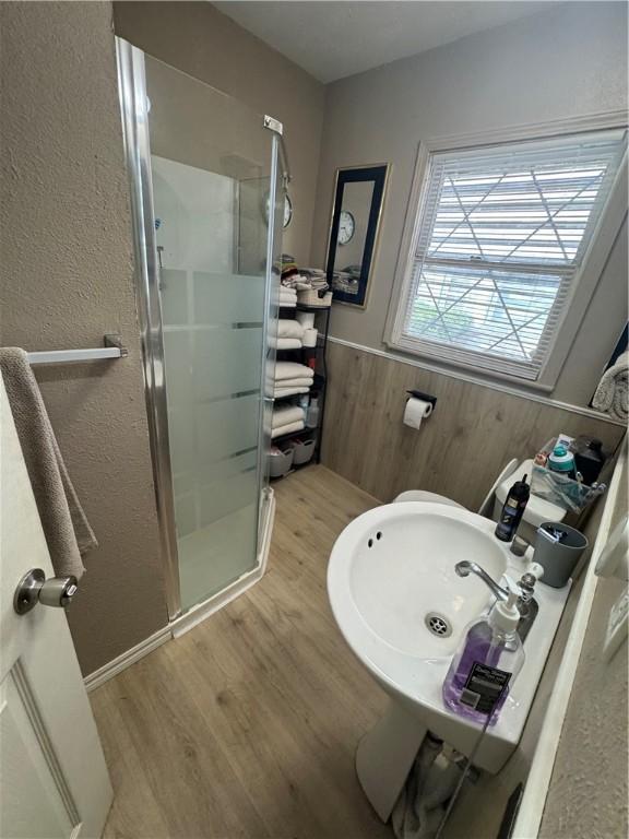 1210 Brentwood Dr, Corpus Christi, TX 78404 - full bath with a textured wall, a shower stall, wood finished floors, and a wainscoted wall
