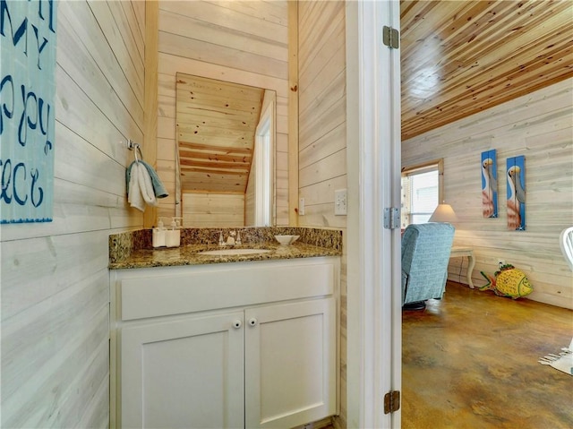 bathroom with wood ceiling, vanity, and wood walls