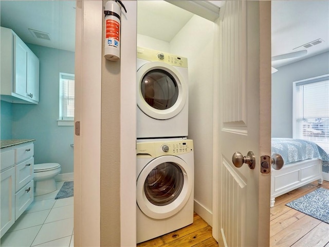 laundry area featuring stacked washer and dryer and light hardwood / wood-style flooring