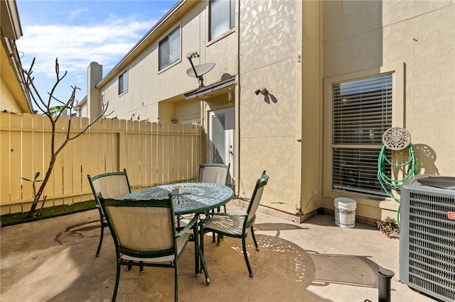 view of patio / terrace with cooling unit, outdoor dining space, and fence