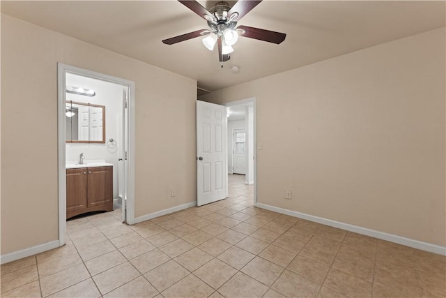 unfurnished bedroom featuring light tile patterned floors, ensuite bath, ceiling fan, and sink