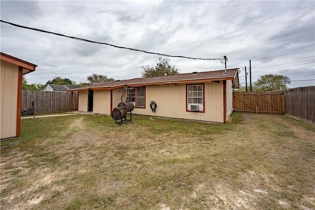 rear view of house featuring cooling unit and a lawn