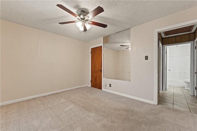 unfurnished bedroom with a textured ceiling, ceiling fan, ensuite bathroom, and light carpet