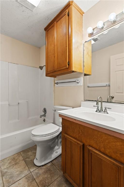 full bathroom with vanity, shower / washtub combination, tile patterned flooring, toilet, and a textured ceiling