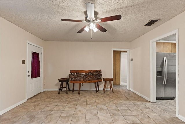 tiled dining space with ceiling fan and a textured ceiling