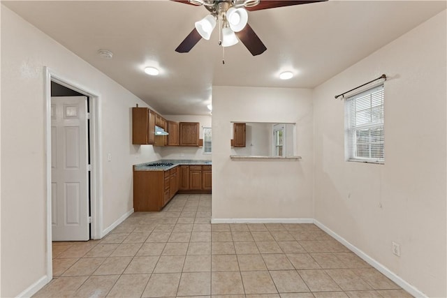 kitchen with ceiling fan, light tile patterned floors, and gas cooktop